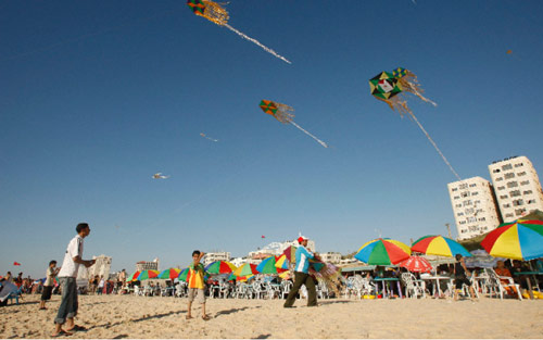 أطفال فلسطينيون يلهون بطائرات ورقية على شاطئ غزة (محمد سالم ـ رويترز)