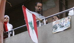 موالٍ للحكومة يعلّق العلم اللبناني على شرفة منزله (رويترز)