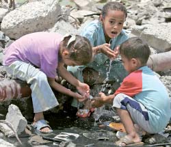 في العراق المحتلّ، الأطفال العراقيون يشربون الماء من «برك الشوارع» في مدينة الصدر (أرشيف ـ كريم رحيم)