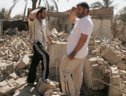 عراقيّان يقفان فوق منزلهما السابق بعد أن قصفته المقاتلات الأميركيّة في عرب جبور جنوب بغداد (لؤي حميد - أ ب)