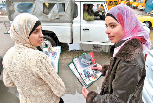 فلسطينيتان من أنصار «حماس» توزعان منشورات خلال احتجاج للحركة في رام الله أمس (إي بي آي)