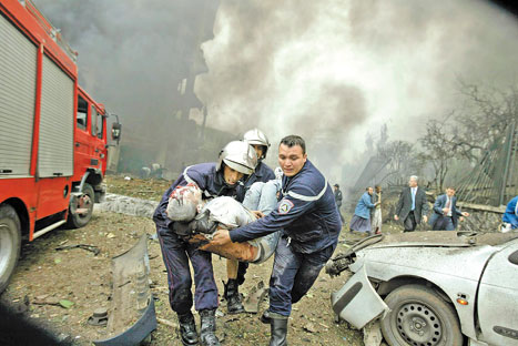 رجال إطفاء جزائريّون ينقلون مصاباً بعد الانفجار أمام مقرّ رئاسة الوزراء أمس (لوافي لاربي - رويترز)