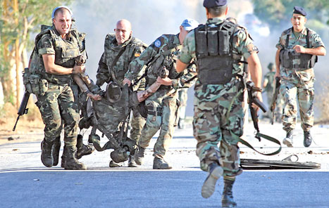 جنود إسبان ينقلون جثة زميلهم في سهل الدردارة أمس (علي ضيا - أ ف ب)