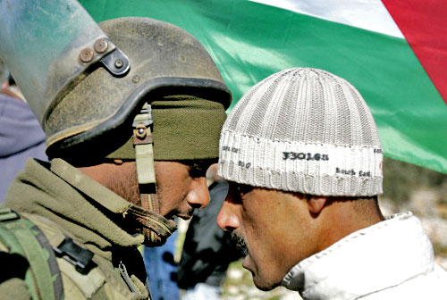 متظاهر فلسطيني يواجه جندياً إسرائيلياً خلال تظاهرة في قرية بلعين في الضفة الغربية أمس (عباس مومني ـ أ ف ب)