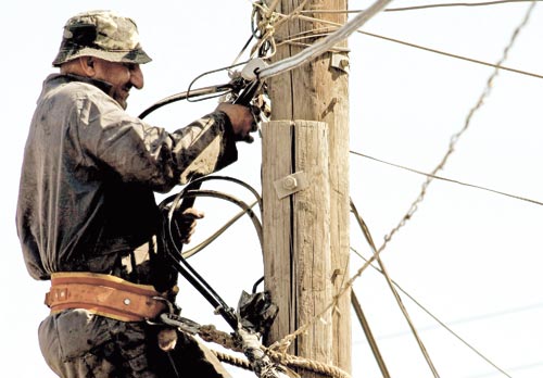 عامل يصلح الكابلات الكهربائيّة على مشارف مخيّم نهر البارد (أرشيف ــ أ ف ب)