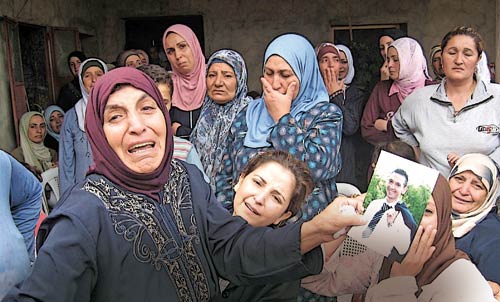 والدة الشهيد العريف علي محمد علي تحمل صورته في بلدته العكاريّة أمس (أ ف ب)