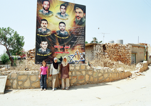 أطفال من بلدة محيبيب تحت لافتة لصور شهداء المقاومة