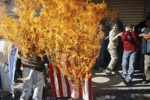 فتية فلسطينيون يحرقون علماً أميركياً في مخيم عين الحلوة احتجاجا على زيارة بوش للمنطقة (علي حشيشو ـــ رويترز