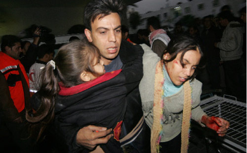 فلسطيني يحمل ابنتيه الجريحتين إلى مستشفى في غزّة أمس (ياسر صايماه - أ ف ب)