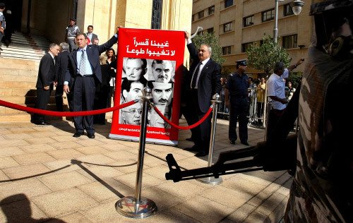 النائبان محمد الحجار وجمال الجرّاح يمسكان بملصق يحمل صور نواب اغتيلوا في المرحلة الأخيرة (رمزي حيدر ــ أ ف ب)