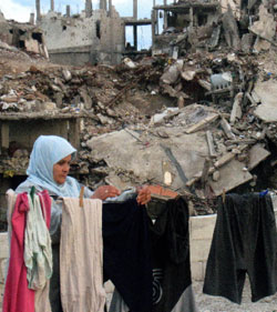 فلسطينية تعلّق الملابس على حبل غسيل أمام مبانٍ مدمرة جرّاء الإشتباكات بين الجيش وعناصر فتح الإسلام (أرشيف)