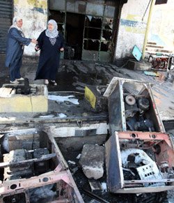 تقفان أمام الدمار الذي لحق بمحطة وقود في شارع سوريا الفاصل بين باب التبانة وجبل محسن (رمزي حيدر ــ أ ف ب)