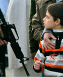 إسرائيلي يمنع طفلاً ووالده من الوصول إلى منزلهما خارج القدس أمس (محمد محيسن - أ ب)