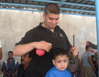 حلاق يقص شعر طفل في باحة مدرسة الاونروا