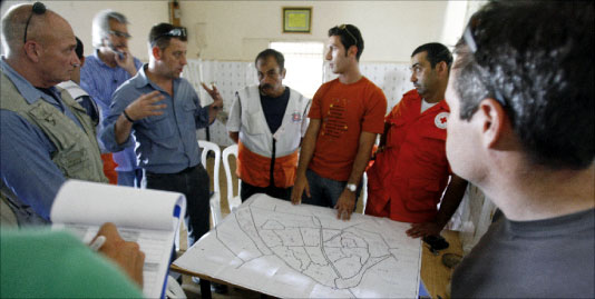 اعضاء من منظمة ماغ لنزع الألغام تناقش مع الصليب الأحمر خريطة لمخيم نهر البارد (باتريك باز - أ ف ب)