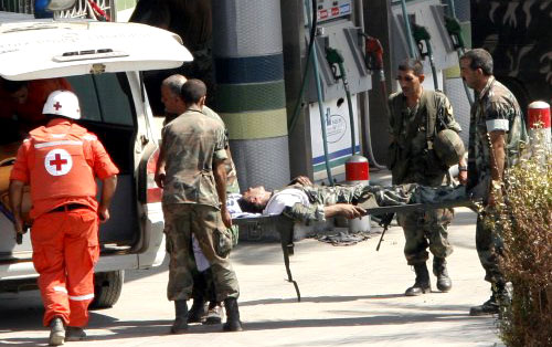جنود من الجيش ينقلون زميلهم الجريح بمساعدة الصليب الأحمر اللبناني (عمر إبراهيم - رويترز)