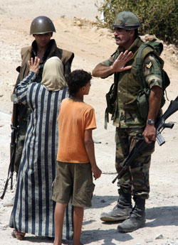 أمراة تحاول اقناع عسكري بالسماح لها بالدخول الى المخيم لتفقد منزلها (رمزي حيدر- أ ف ب)