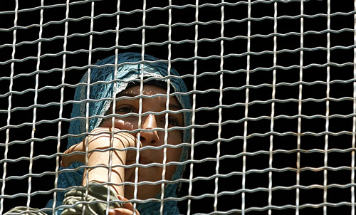 فتاة فلسطينية تراقب الاعتصام من خلف شباك مدرسة كوكب في البداوي (مروان نعماني - أ ف ب)