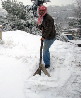 علي حمية يجرف الثلوج عن سطح منزله في طاريا (رامح حمية)