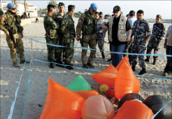 عناصر من القوى الأمنية اللبنانية واليونيفيل يعاينون مجموعة من البالونات على شاطئ صور (ا ف ب)