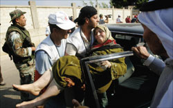 إمراة مسنة أثناء نقلها إلى  مخيم البداوي امس (مات دونهام - أ ب)