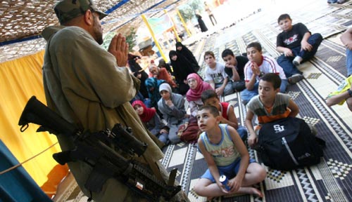 أطفال يستمعون بدهشة إلى محاضرة يلقيها مقاوم خلال مخيم صيفي تنظمه جمعية «شباب» التابعة لحزب الله في جنوب لبنان (حسن بحسون)