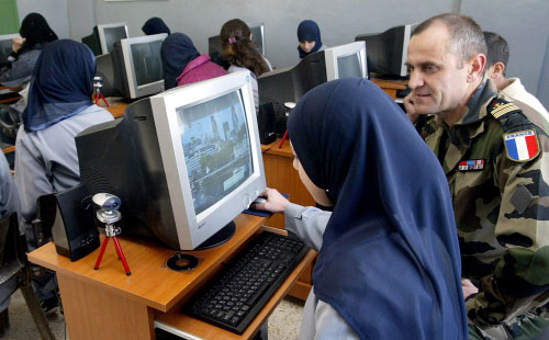ضابط فرنسي يراقب طالبة لبنانية تستخدم حاسوباً قدم هبة من كتيبته إلى مدرسة صريفا (ا ف ب)