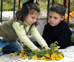 نور ومحمد يضعان زهور على ضريح شقيقتهما الشهيدة نور العابد في ذكرى مجزرة النبطية الفوقا