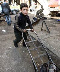 طفل يجر عربة حديدية أمام  أحد المحلات في طرابلس (أرشيف)