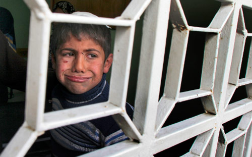 طفل فلسطيني جريح يطل من نافذة في شمال غزة أمس (ماجد حمدان - أ ب)