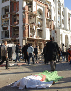 جثّة ملفوفة بالعلم الجزائري قرب المباني التي استهدفتها التفجيرات الانتحارية في العاصمة الشهر الماضي (أ ب) 