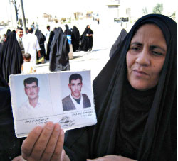 عراقيّة ترفع صورتي قريبيها المعتقلين بانتظار الافراج عنهما في بعقوبة (أ ف ب)