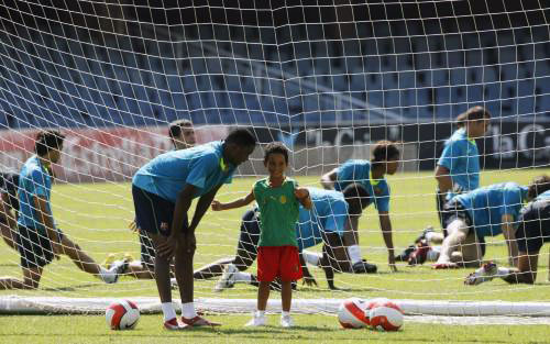 الكاميروني إيتو يتكلم مع إبنه وخلفه لاعبو برشلونة خلال التمارين أمس (ألبرت جيا ـ رويترز)