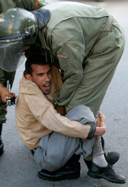 شرطي مغربي يعتقل متظاهراً يطالب بحقوق المعوّقين جسديّاً في العاصمة الرباط  (رفاييل مرشانت ــ رويترز) 
