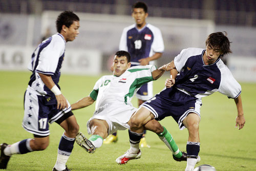 العراقي يونس محمود بين ثلاثة لاعبين سنغافوريين (أ ف ب)