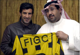 فيغو حاملاً قميص نادي الاتحاد الى جانب رئيس النادي منصور البلوي (أ ف ب)