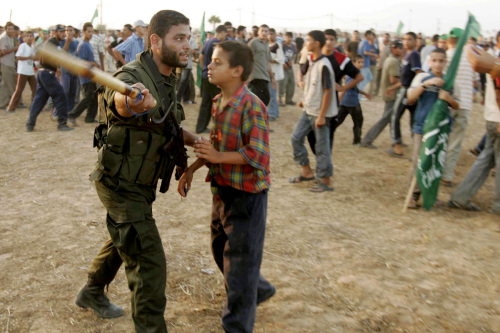 عنصر من القوّة التنفيذية في «حماس» يمنع أحد مناصري الحركة من الاقتراب من بوّابة معبر رفح خلال تظاهرة احتجاجية (أرشيف - رويترز)