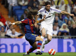 سباق على الكرة بين لاعب ريال سيرجيو راموس وقائد برشلونة كارلس بويول (سيرجيو بيريز ــــ رويترز)