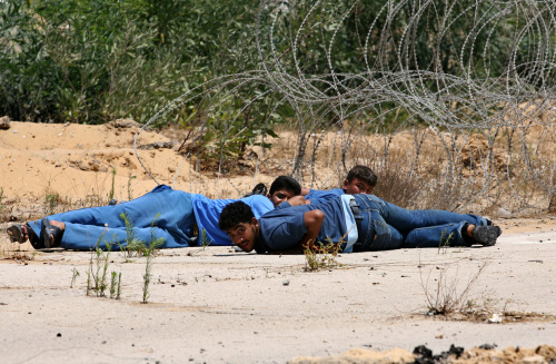 فلسطينيون يختبئون من الرصاص الاسرائيلي على الحدود بين غزة والأراضي المحتلّة أمس (سيد خطيب - أ ف ب)