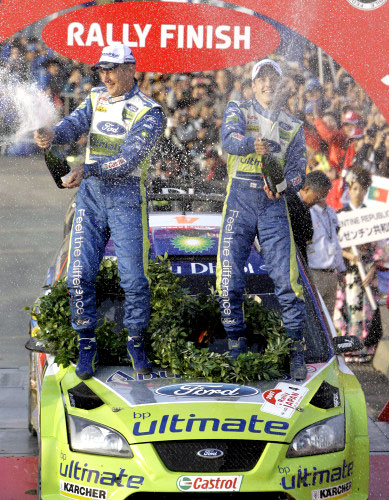 هيرفونن (إلى اليمين) وملاحه ليتينن يحتفلان فوق سيارتهما «فورد فوكوس» (شوجي كاجيياما ــ أ ب)