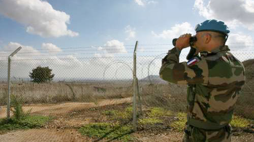 جندي من القوات الدولية في الجولان المحتل يراقب الحدود السورية مع فلسطين المحتلة (رويترز)