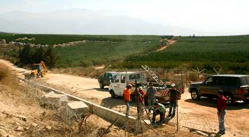 عمال إسرائيليون يصلحون سياجاً في مزارع شبعا المحتلة في آب الماضي (رويترز)