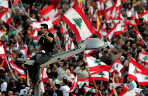 لبناني تسلّق عمود إنارة لرفع العلم خلال تظاهرة أمس في ساحة الشهداء (أ ب)