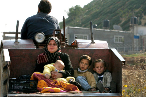 أم فلسطينية وأطفالها الثلاثة يتنقلون في اليّة زراعية في غزة أمس (أ ب)