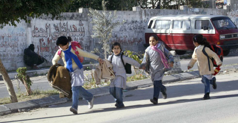 فتيات فلسطينيّات تركضن بجانب عنصر أمني من حركة حماس في غزّة أمس (أ ف ب)