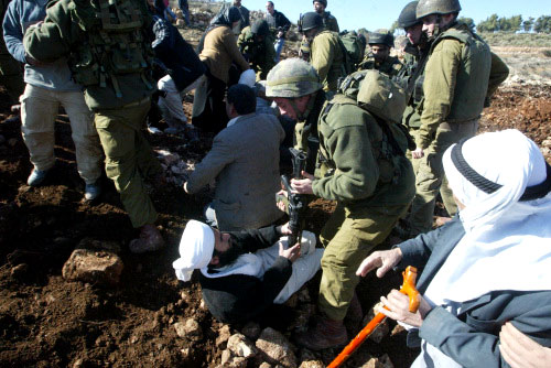 جندي إسرائيلي يضرب رجل دين فلسطينياً أثناء احتجاج على بناء الجدار الفاصل في القدس المحتلة أمس (أ ف ب)