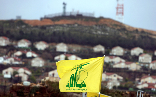 علم حزب الله يرفرف على الحدود في بلدة كفركلا وتبدو خلفه مستوطنة اسرائيلية (أ ف ب)