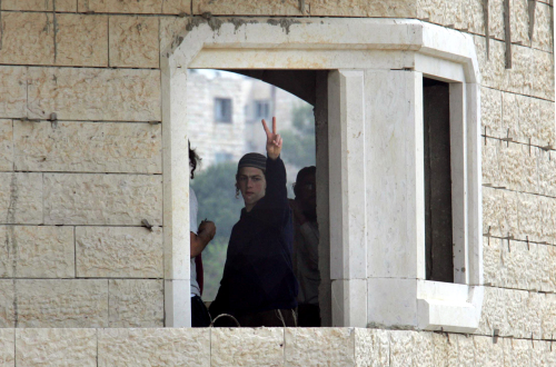 مستوطن يرفع علامة النصر في منزل فلسطيني في الخليل أمس (حازم بدر - أ ف ب)
