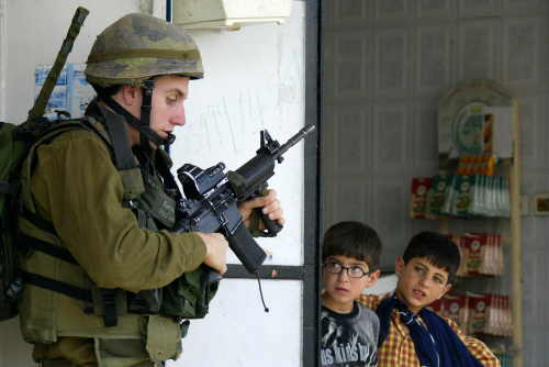 أطفال فلسطينيون يراقبون قوات الاحتلال خلال عمليات مداهمة في الضفة أمس (حازم بادر - أ ف ب)