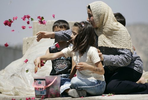 فلسطينيون ينثرون الورود على جثمان شهيد خلال تشييعه في جنين أمس (محمد تركمان - رويترز)